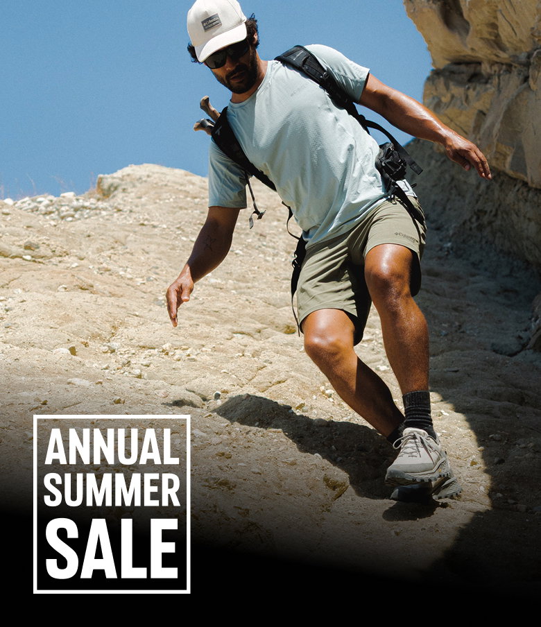 A man in hiking gear walking in a rocky landscape with text: ANNUAL SUMMER SALE