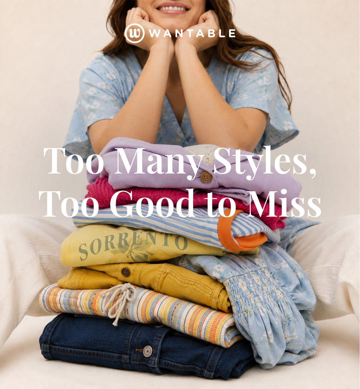 Smiling woman holds a colorful stack of End of Season clothing.