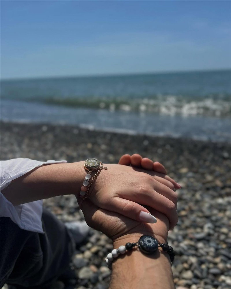 A couple wearing Mountain and Sea touch bracelets by the water