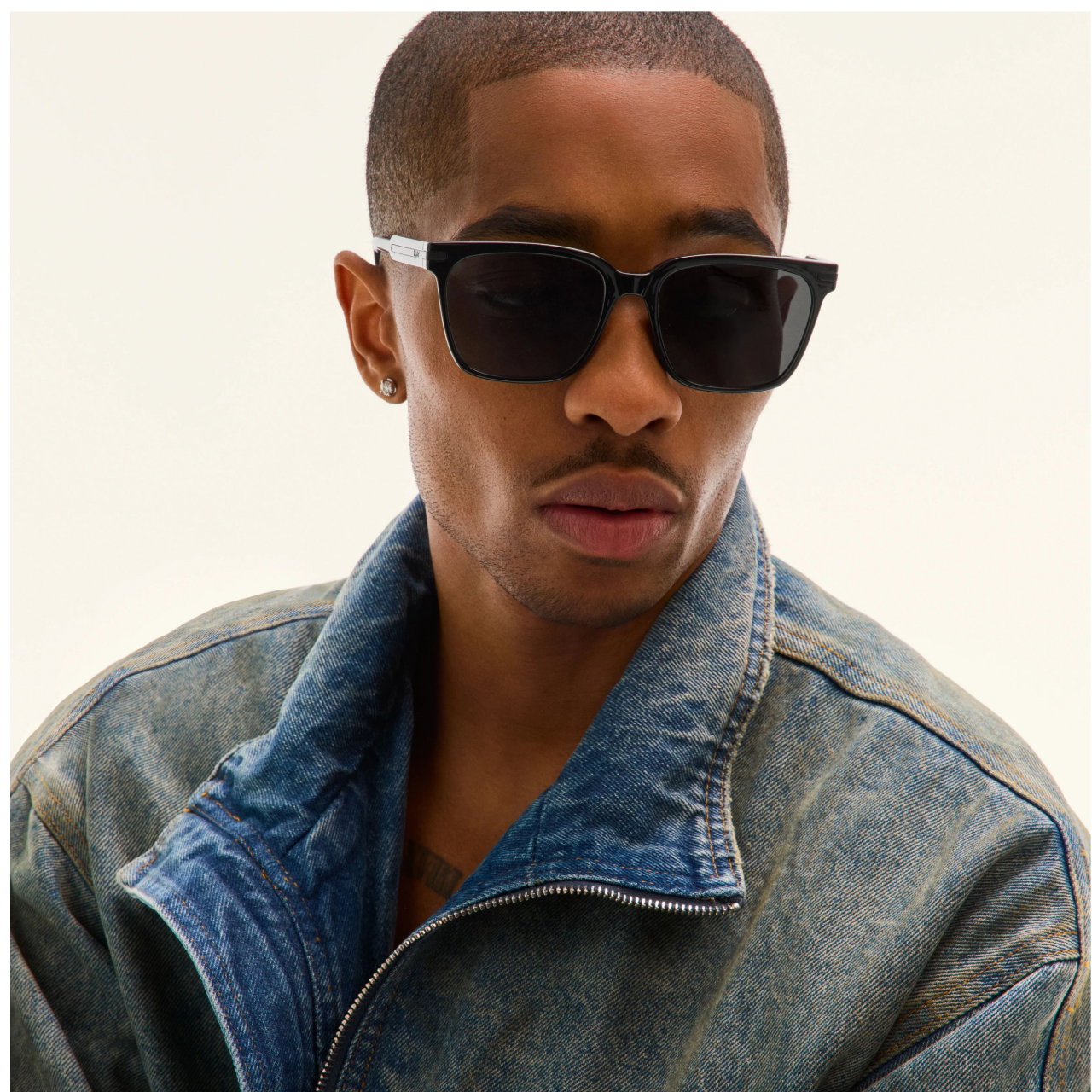 Image of man wearing square black sunglasses looking to the side