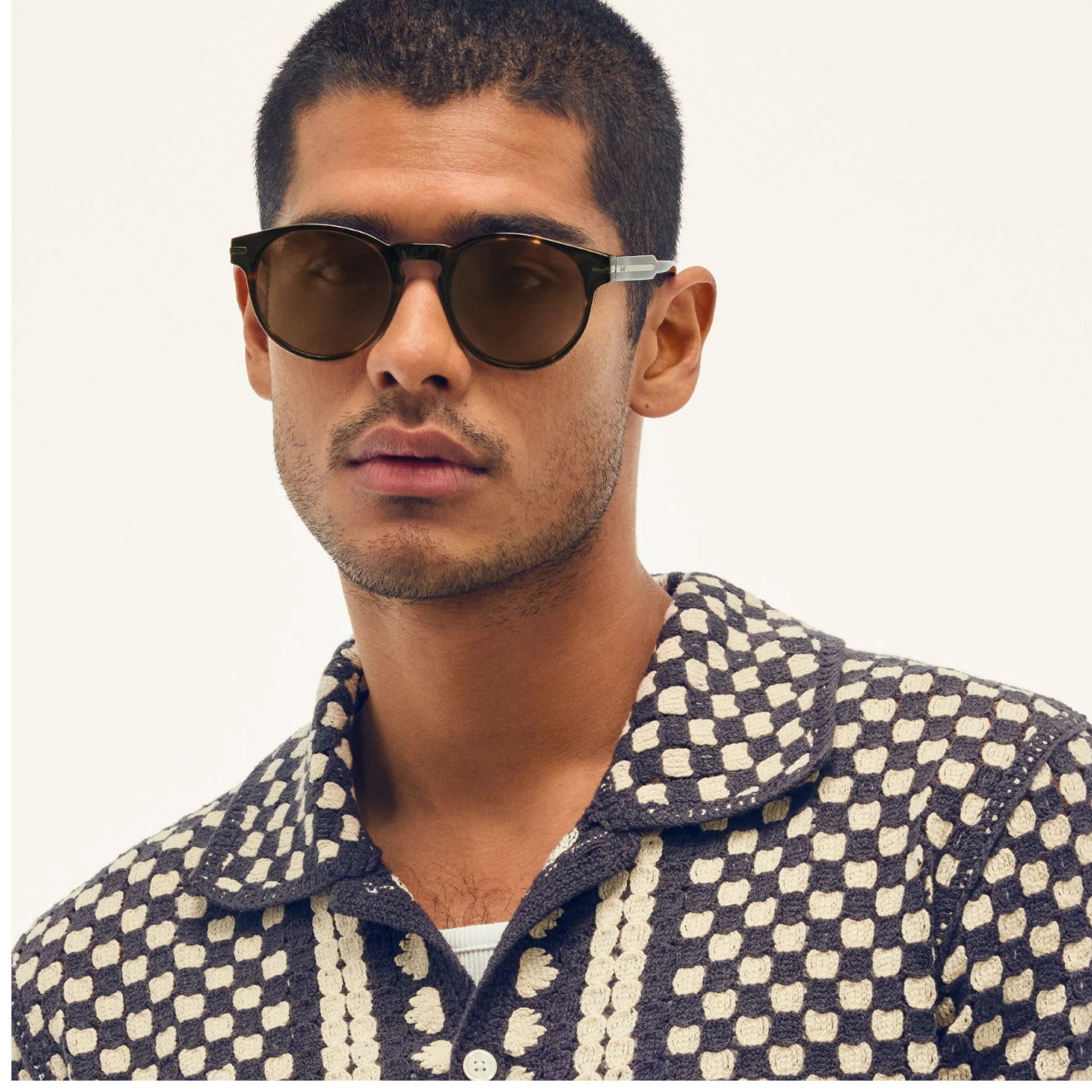 Image of man wearing round tort sunglasses looking at the camera