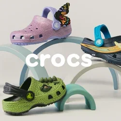 Vijf kleurrijke kindersabots met decoratieve bedeltjes, gerangschikt op pastelkleurige bogen tegen een neutrale achtergrond.