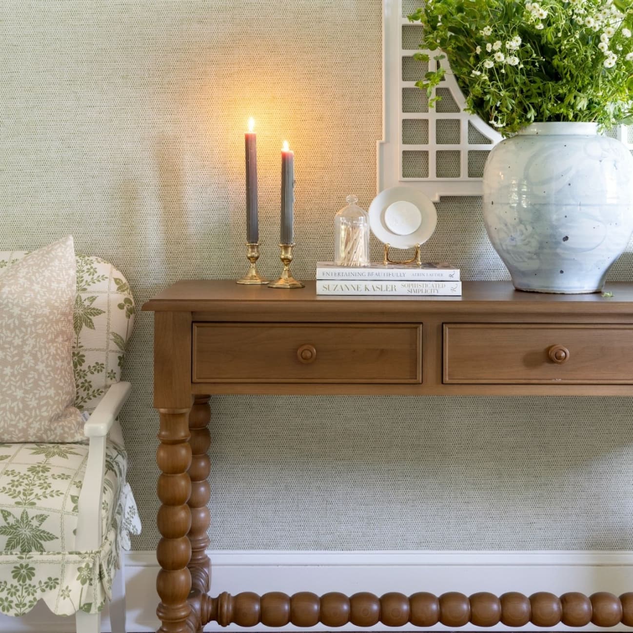 Foyer with console table table with decor on top like vase of flowers, candlesticks, and books.
