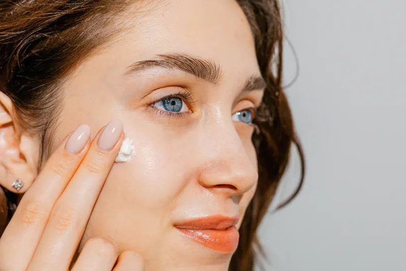 Person sweeping moisturizer onto upper cheek