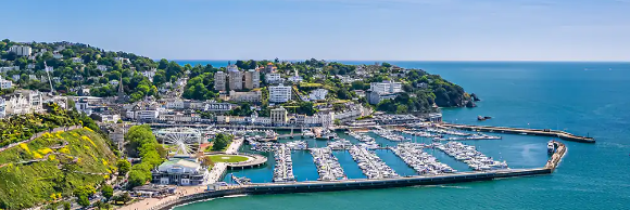 Aerial view of a cityscape featuring a historic building, lush greenery, and a clear blue sky.