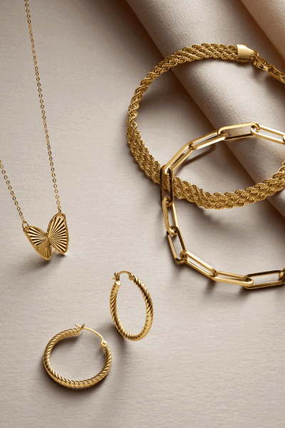 Yellow gold butterfly pendant necklace, twisted hoop earrings, rope bracelet and paperclip chain bracelet.