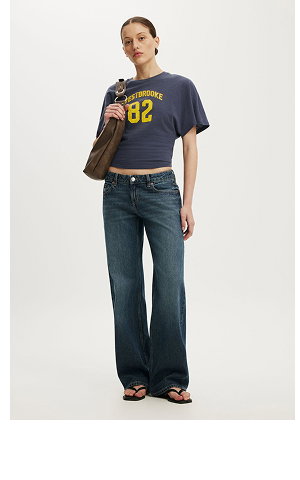 Model wearing navy graphic t-shirt with "02" print and dark wash wide-leg jeans