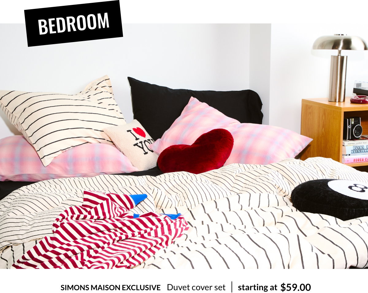 Bedroom. A casually unmade bed with a striped bedspread and several colorful pillows, including the I Love You bouclé removable-cover cushion 29$.