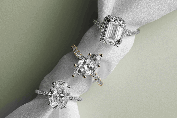 Oval, marquise and emerald-cut engagement rings with diamond-accented bands.