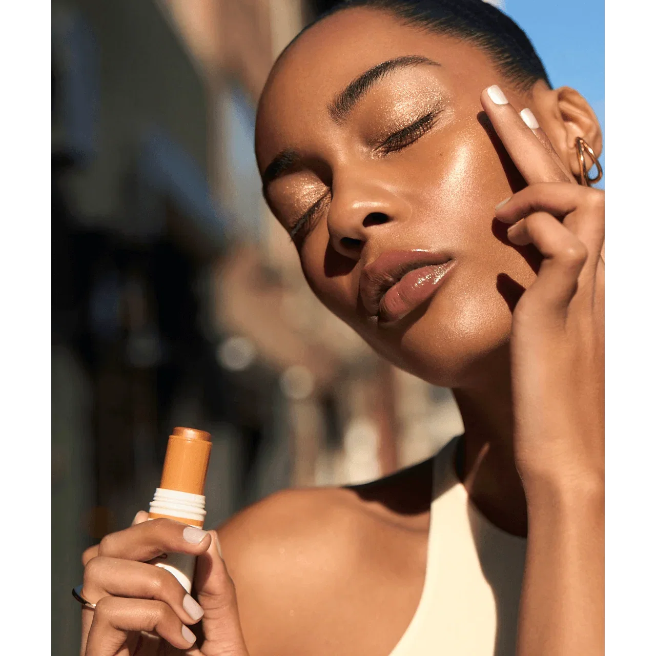 Woman applying Skin Enhancer Multi-Stick under the sun.