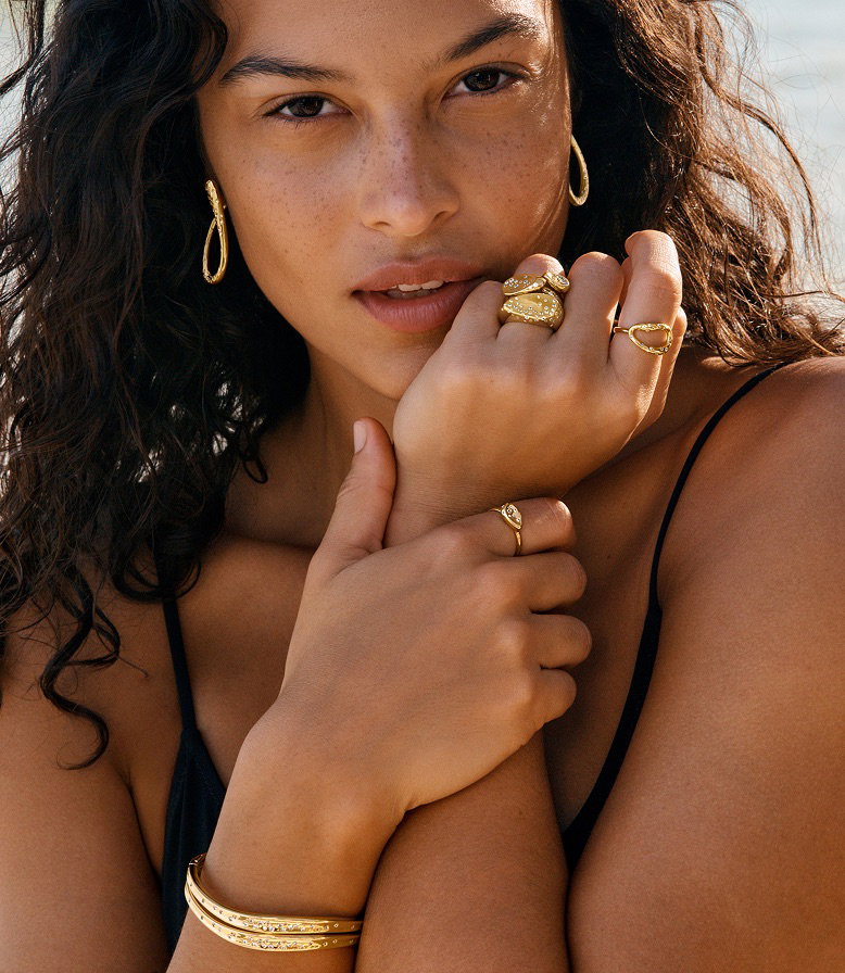 A model wears chunky 14k gold-plated jewellery under the glow of the sun.