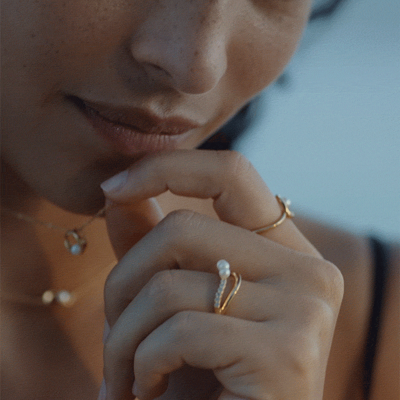 A close-up of a model's hand shows pearl rings and necklaces from Pandora.