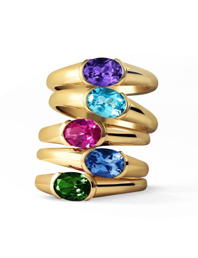 Stacked yellow gold gemstone rings featuring colorful oval-cut center stones.