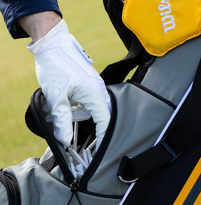 Golfer wearing glove getting tees from golf bag
