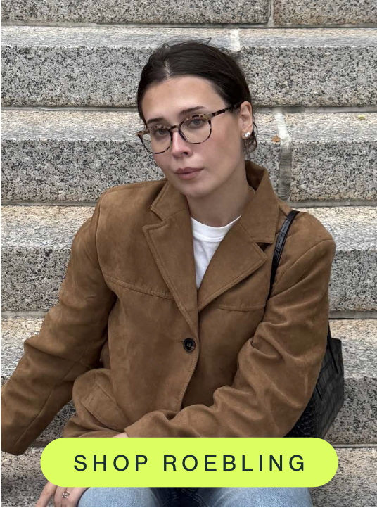 A person wearing tortoiseshell blue light glasses and a brown jacket sits on stone steps. A bright "Shop Roebling" button highlights the featured frame style.