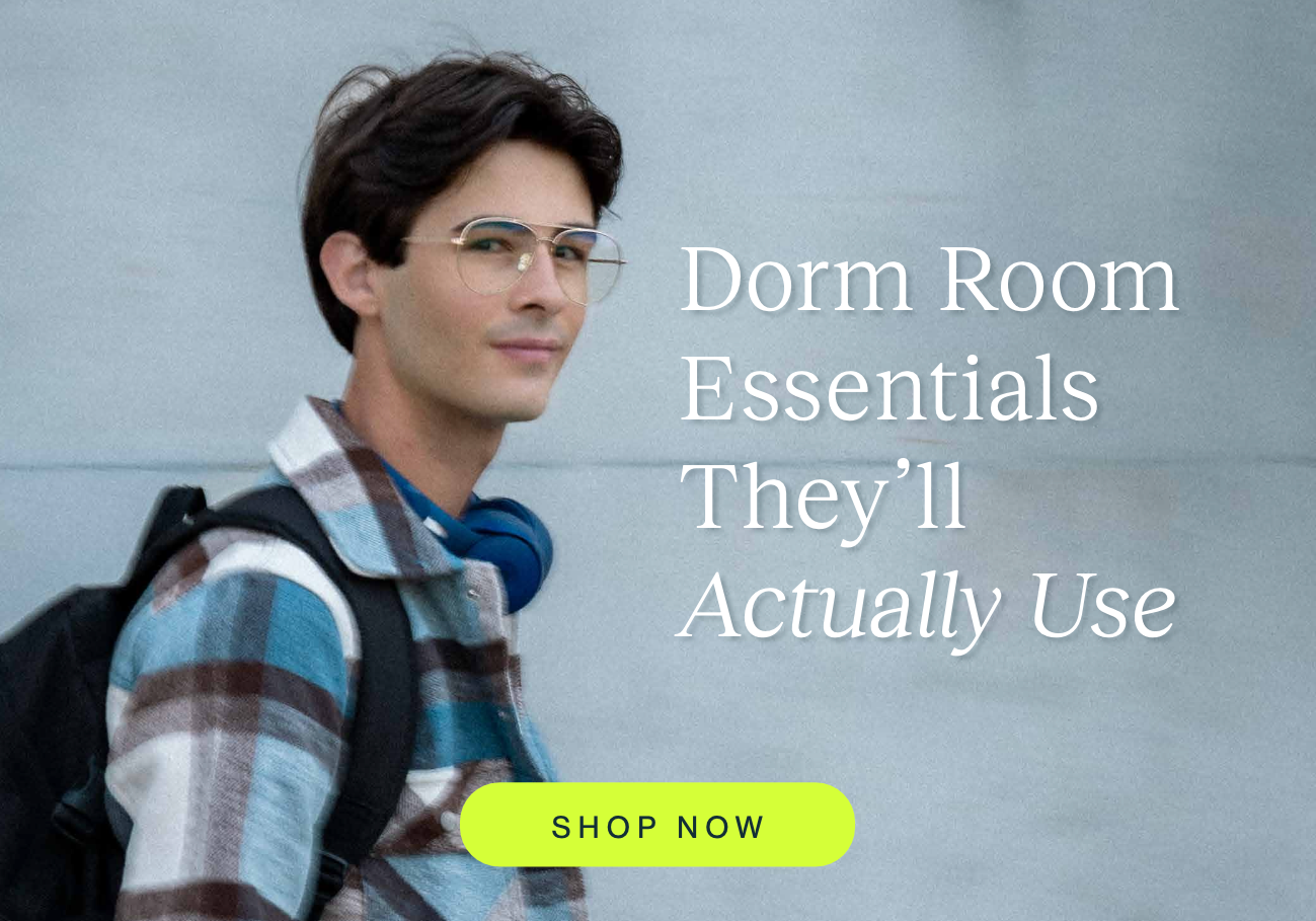 A student wearing blue light glasses, a backpack, and headphones walks outdoors beside the headline "Dorm Room Essentials They'll Actually Use." A bright "Shop Now" button invites shoppers to explore eyewear designed for everyday comfort during studying, screen time, and campus life.