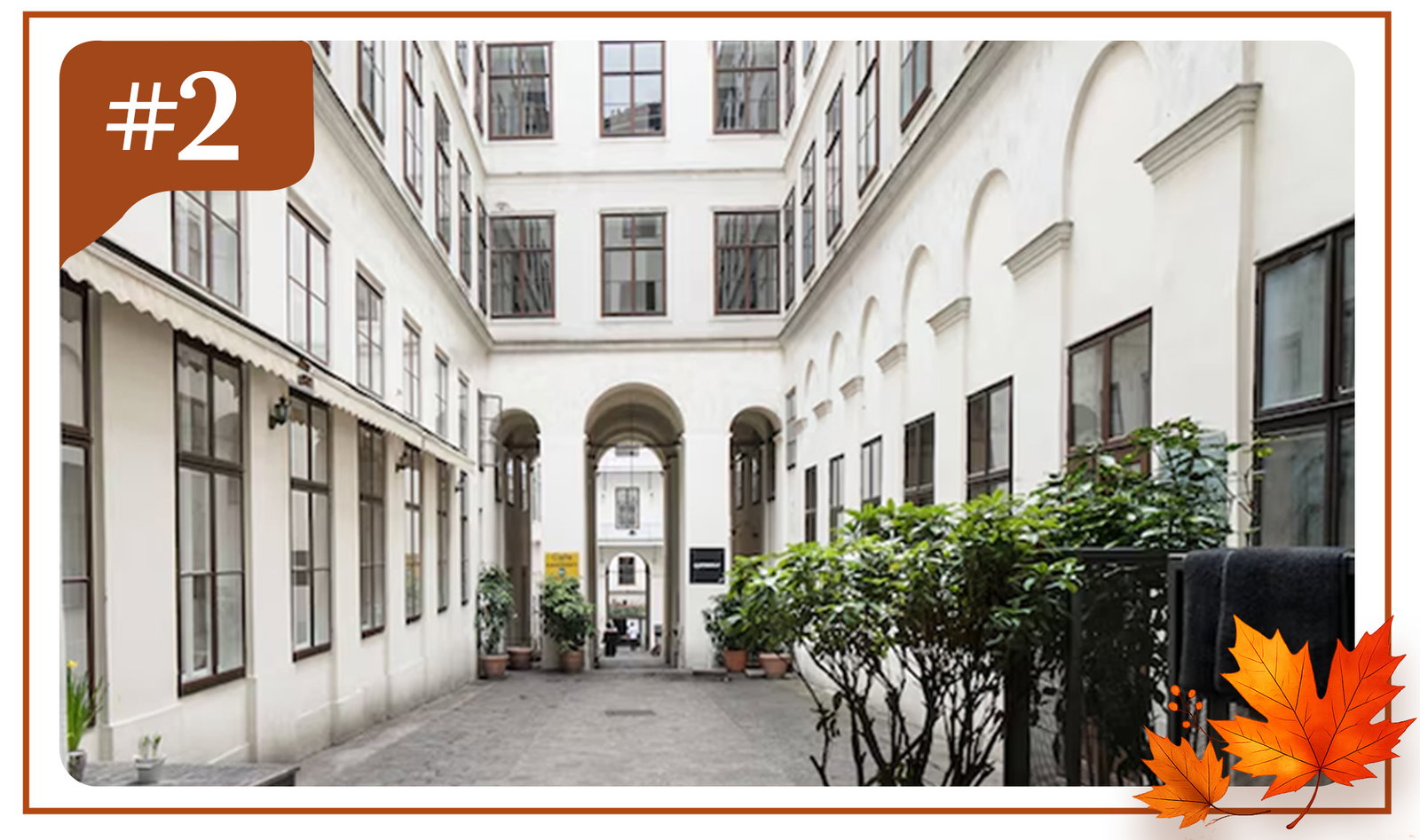 Bright European courtyard with arched passageways, tall windows, and potted greenery.