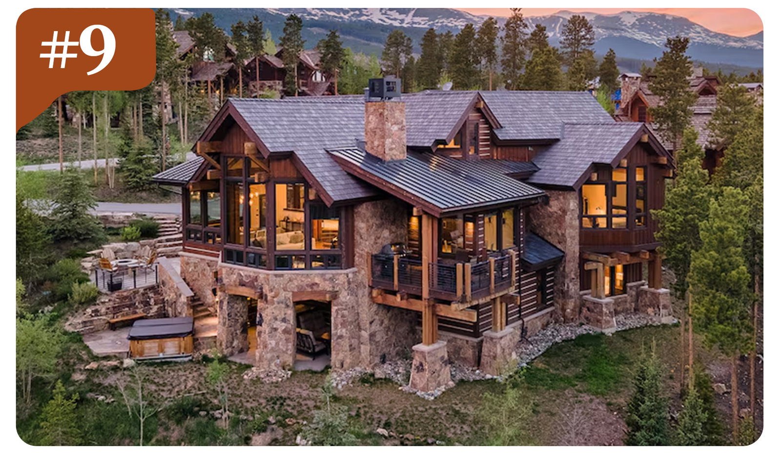 Elegant mountain retreat with stone accents, spacious terraces, and snow-capped peaks beyond.