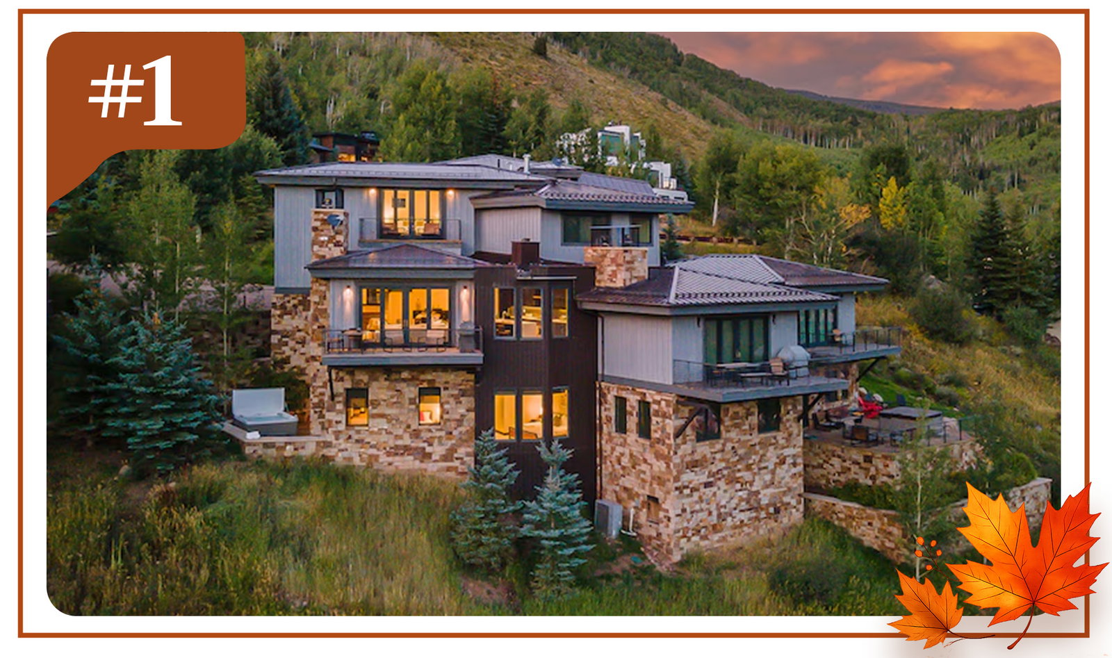 Modern stone-and-wood mountain home with illuminated windows, surrounded by forested hills at sunset.