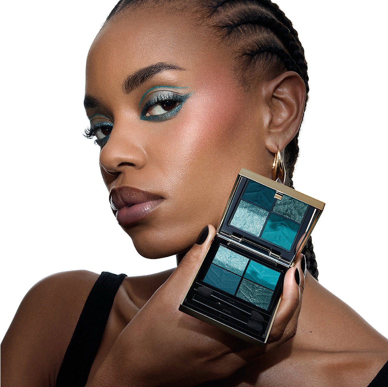 A woman with dark skin showcasing a graphic turquoise eyeshadow look while holding the matching YSL palette.