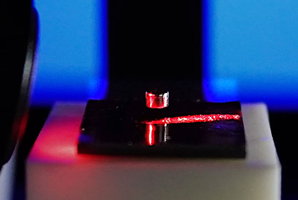 A small, cylindrical magnet levitates above a diamagnetic graphite stabilizer while being probed by a laser beam.
