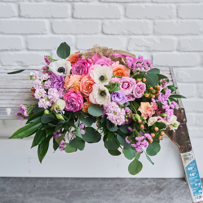Roses and ranunculus bouquet resting on a bench