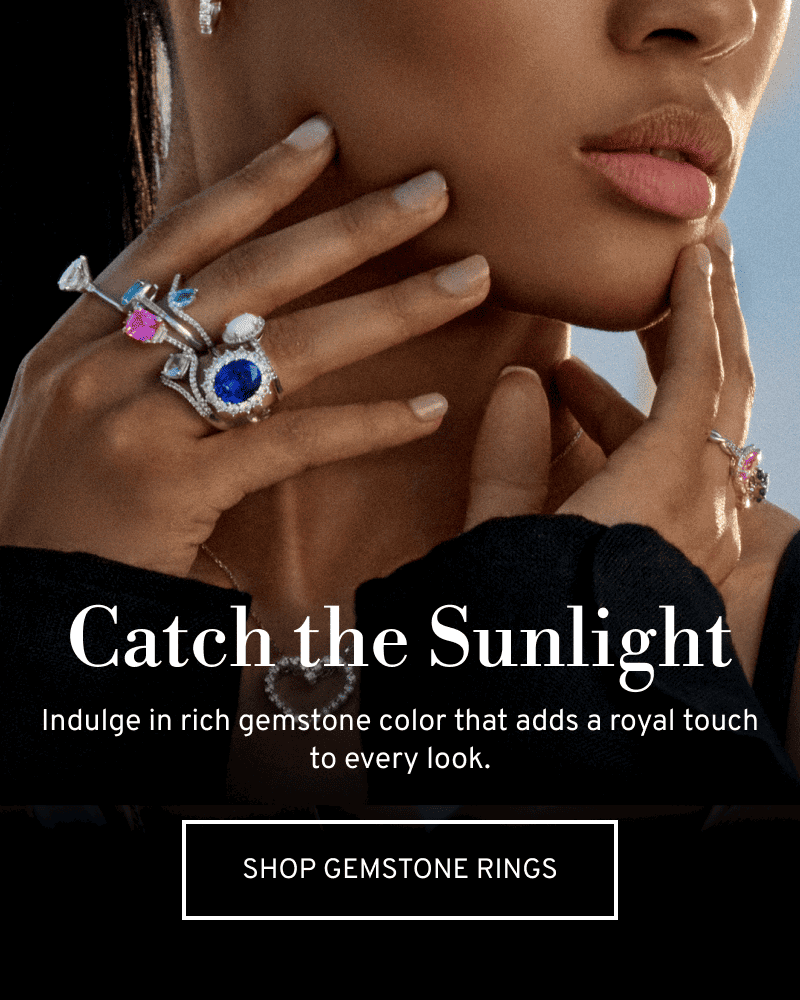 Model touching her face with colorful rings. Catch the Sunlight. A royal touch for every look. Click to Shop Gemstone Rings