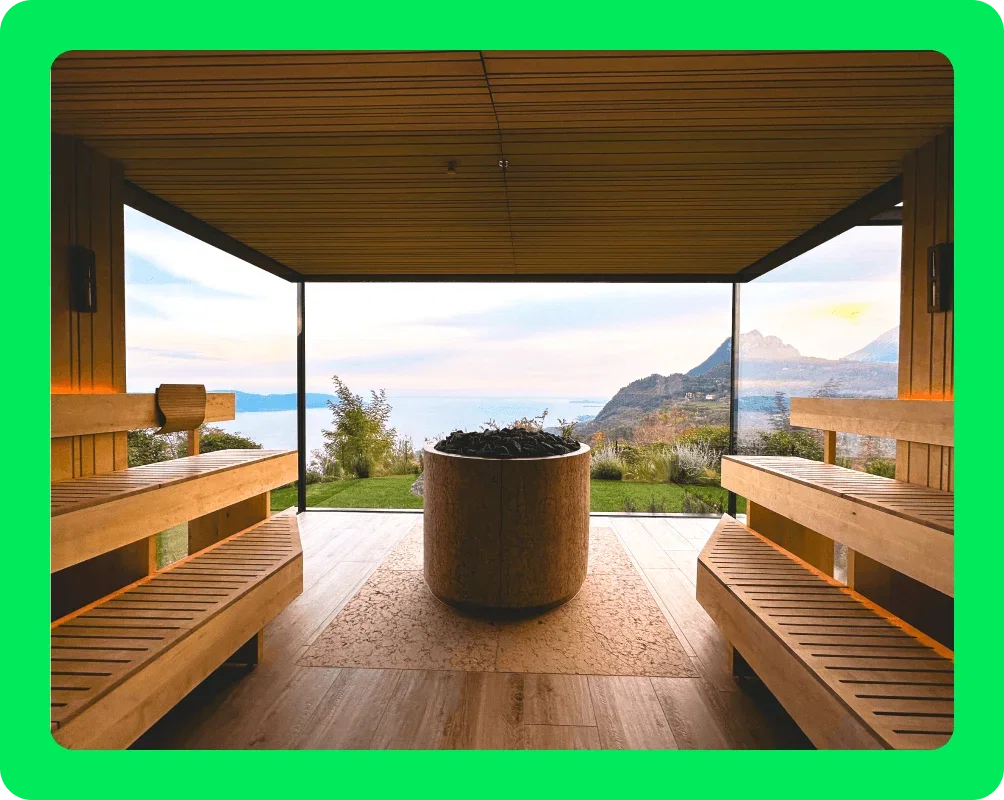 Image Description: A sauna with a vessel of hot coals. A panoramic window overlooking mountains and water is in the background.