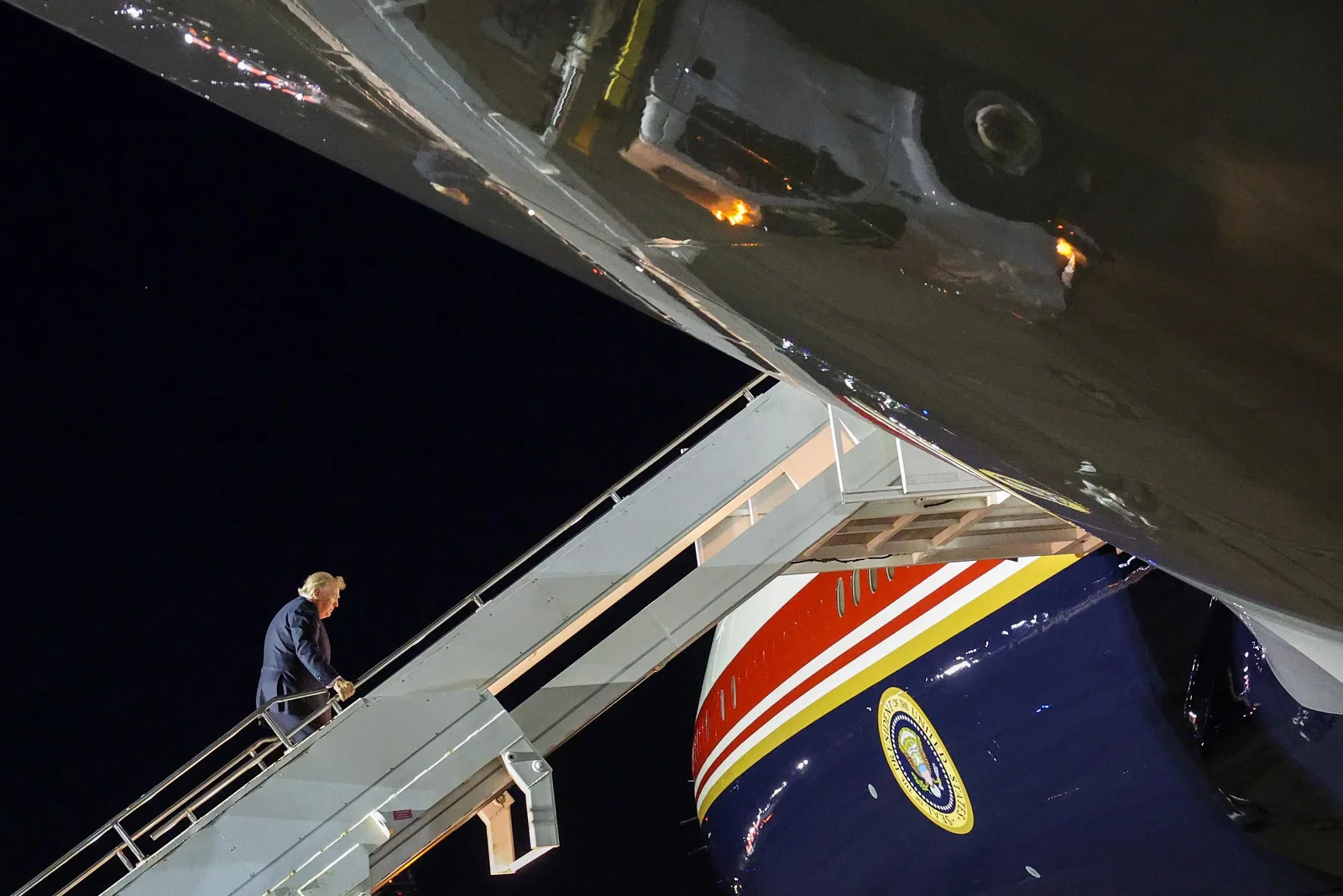 Donald Trump climbs a flight of stairs into Air Force One.