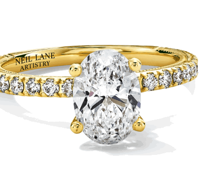 An oval diamond engagement ring in yellow gold with pavé-set diamonds.