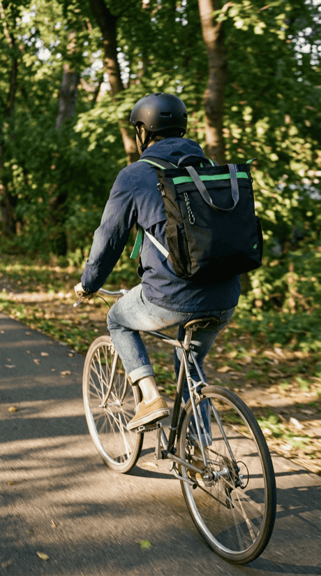 Professional commuting by bike carrying the 25L Convertible Carryall in Black Multi, backpack mode
