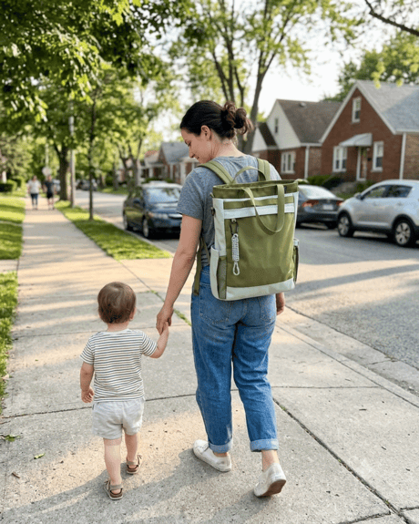 Parent wearing the 25L Convertible Carryall as a backpack while walking hand-in-hand with a toddler