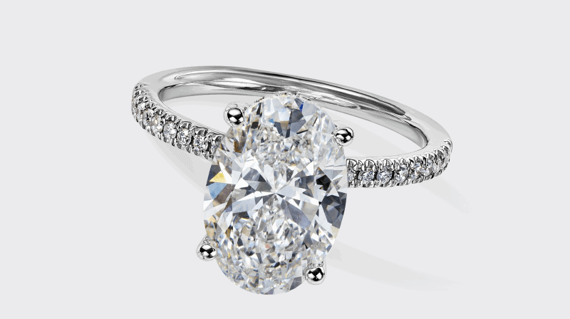 An oval diamond solitaire ring in white gold with a pavé-set diamond band.