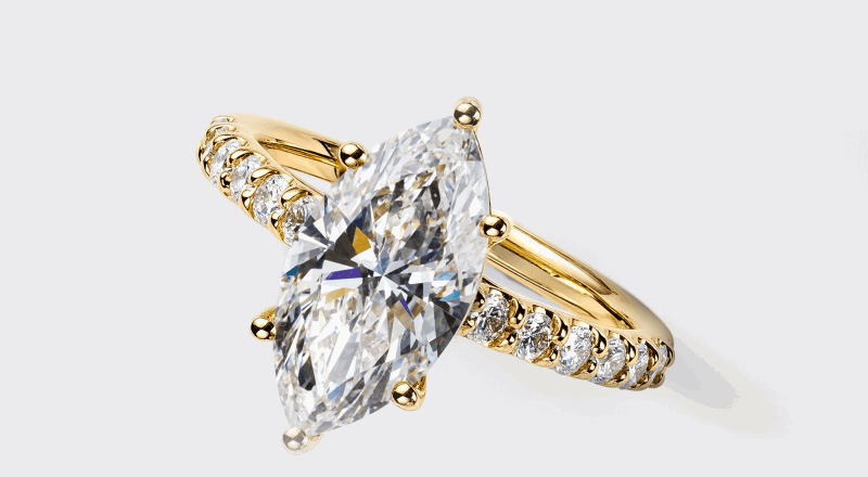 A marquise diamond ring in yellow gold with diamond accents along the band.