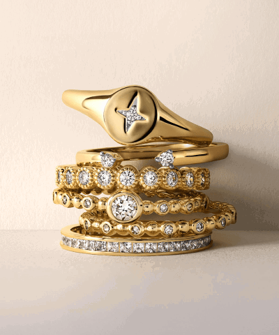 Stack of yellow gold rings featuring diamond accents, a signet ring and textured band designs.