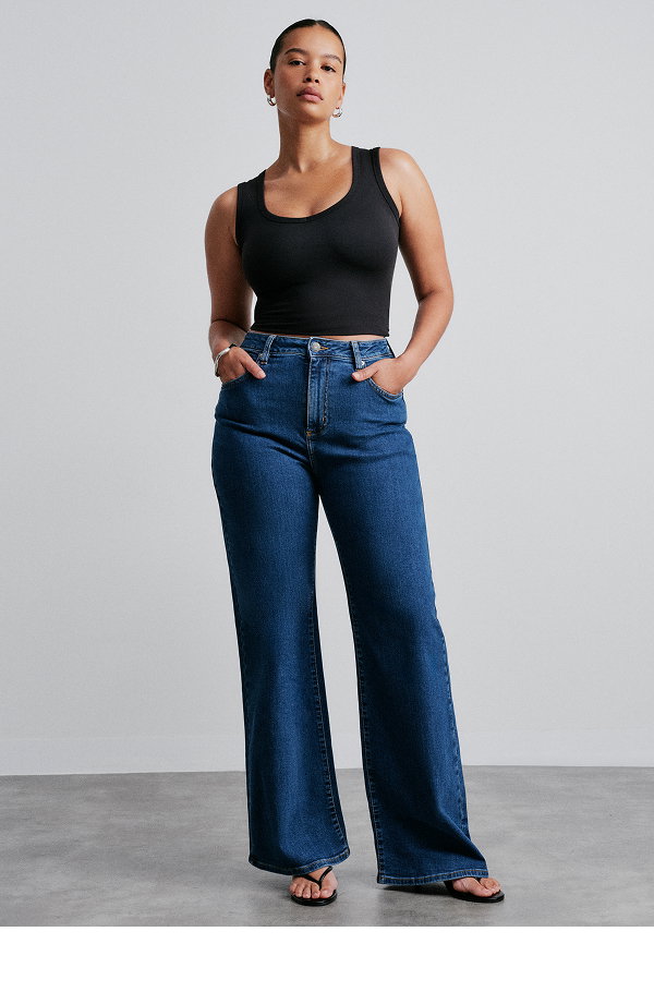 Woman wearing black tank top and blue wide-leg jeans