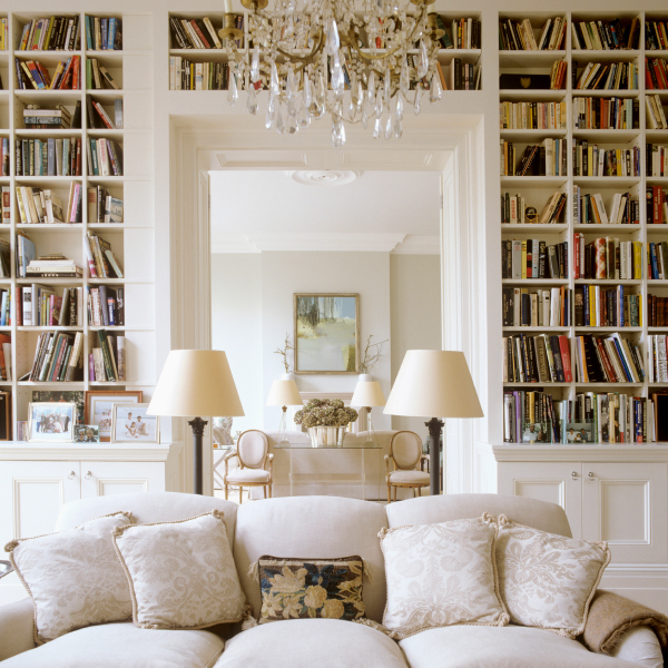 White sofa in living room with wall showing bookshelf filled with books