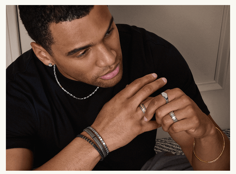 Male model with mixed-metal rings, stacked beaded & metallic bracelets, chain necklace & studs.