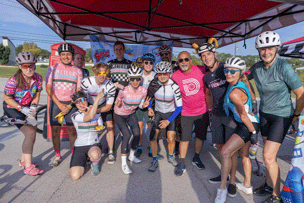 Cyclists celebrating together under a tent at a Trek 100 Texas rest stop