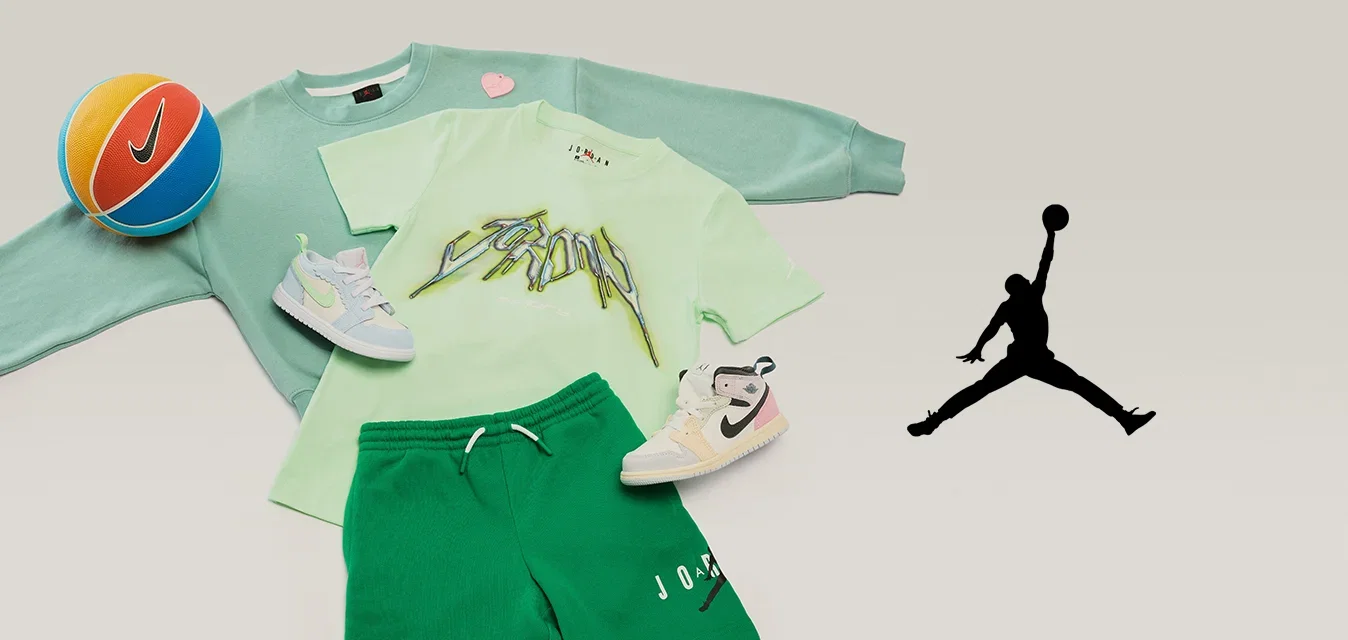Grüner Sweatshirt, hellgrünes Grafik-T-Shirt, grüne Shorts, zwei weiße Sneakers und ein orange-blauer Nike-Basketball auf hellem Hintergrund.