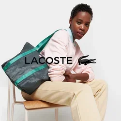 Tote-Bag aus schwarzem, strukturiertem Material mit grünen Trägern, versehen mit einem geometrischen Muster und einem pinken Logo. Verstellbarer Trageriemen für Vielseitigkeit.