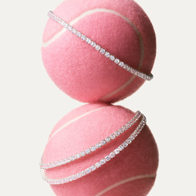 Close-up of model styling Pandora tennis bracelets on pink tennis balls.
