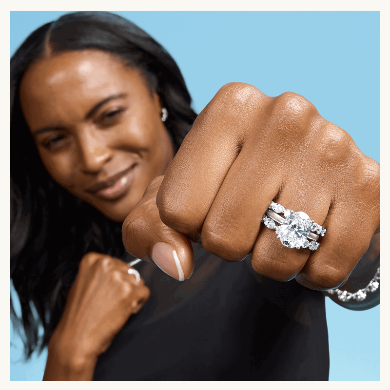 Model with thick, oval-cut diamond ring & eternity bands.