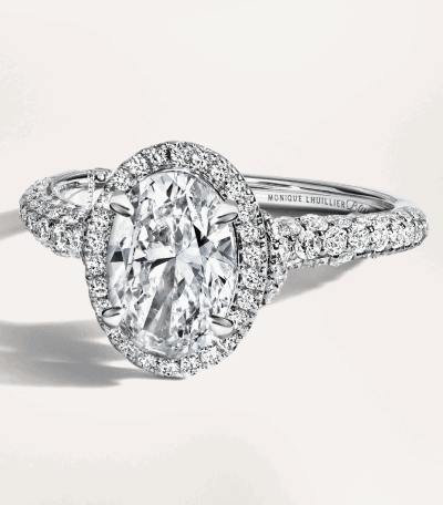 An oval diamond halo ring in white gold with pavé-set diamonds and a twisted band.