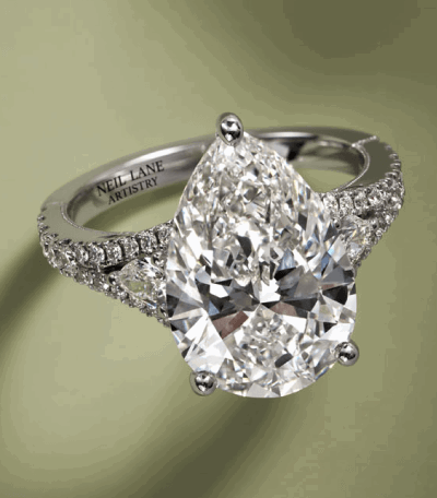 A pear-shaped diamond ring in white gold with pavé-set diamonds and a split shank band.