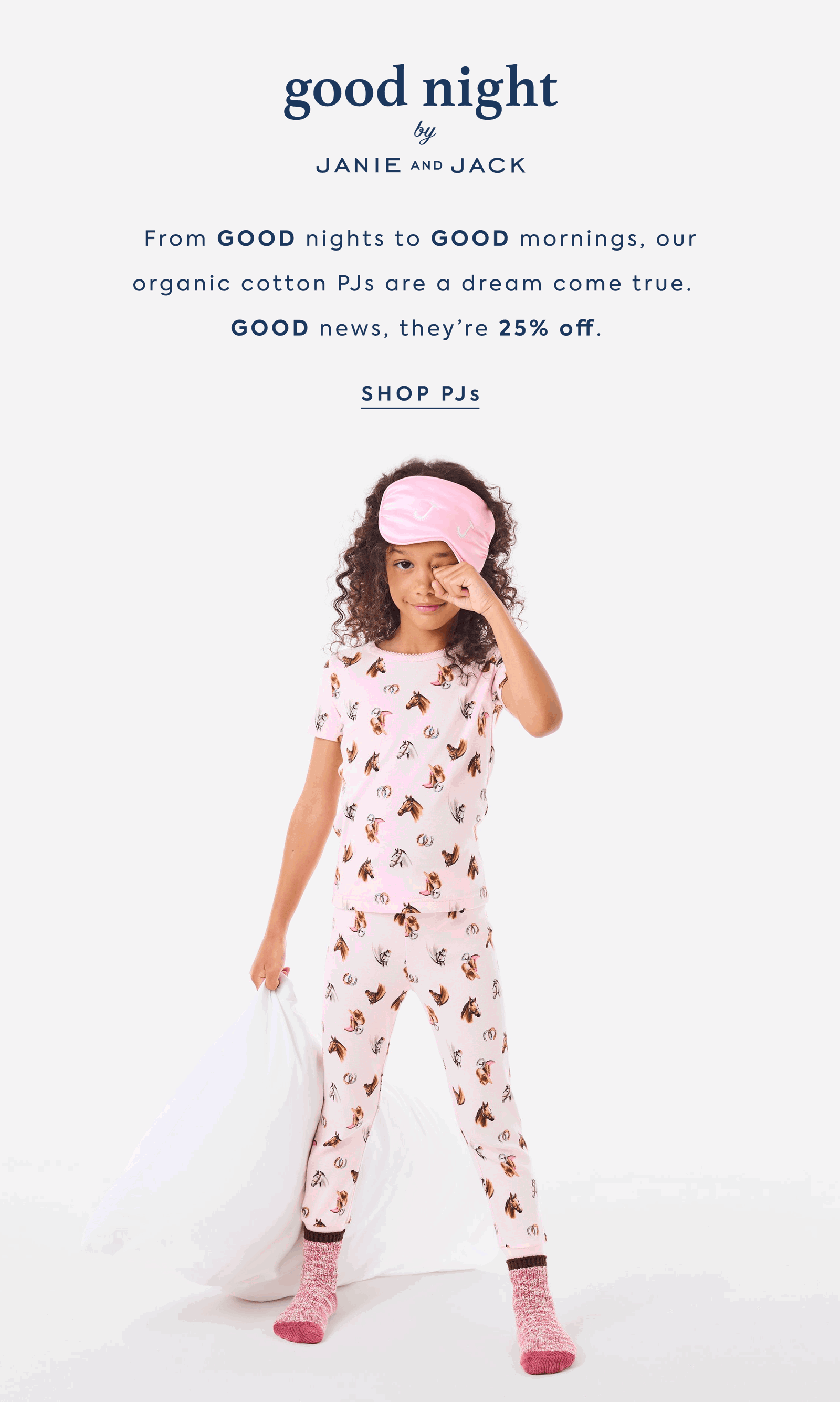 Girl in pink horse-print pajamas with sleep mask holding a pillow