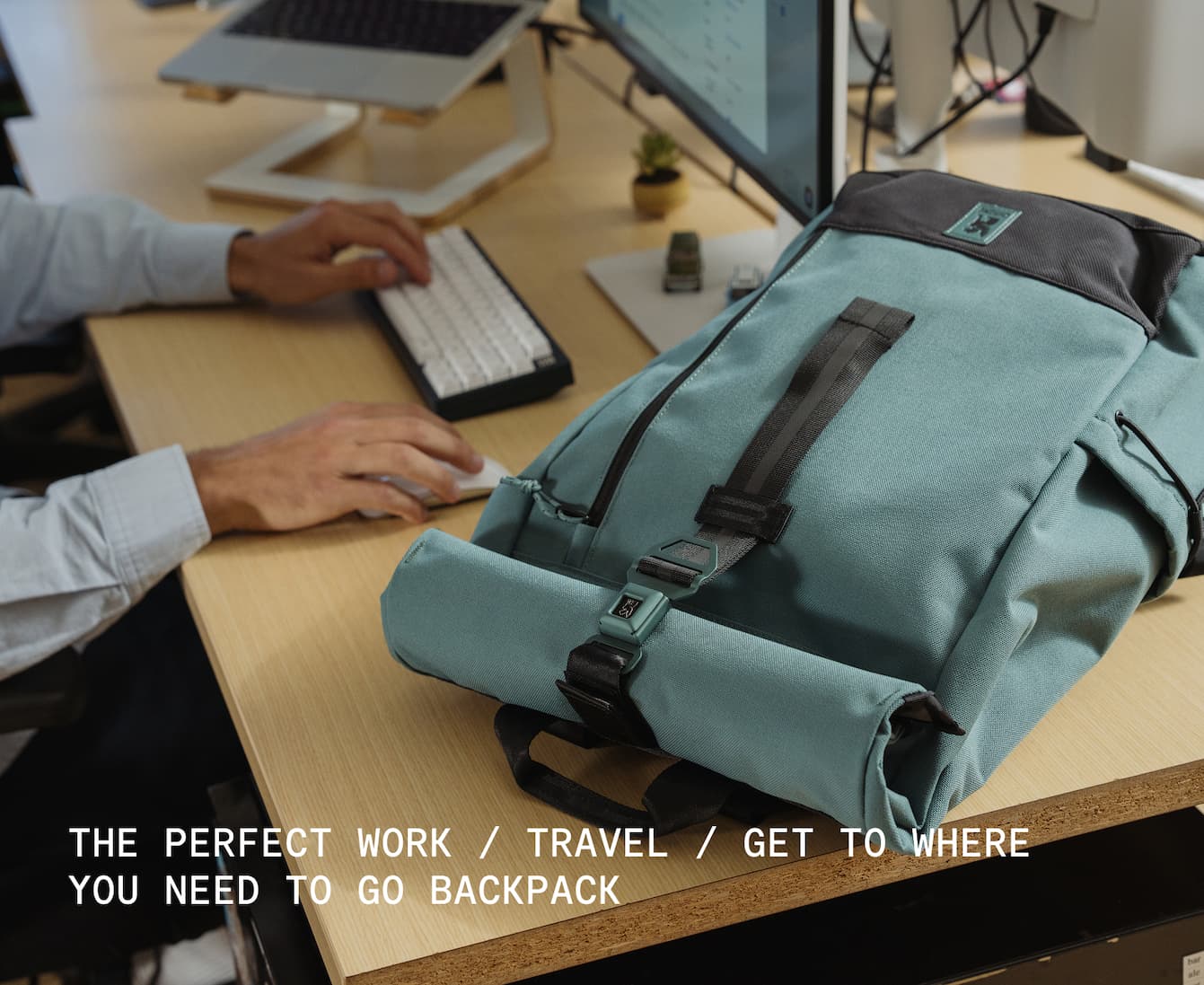 A guy at work sitting by the new Recruit 26L Pack in Steel Blue