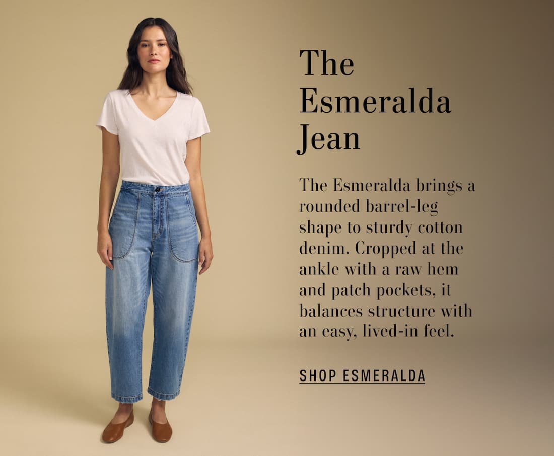 Image of model wearing Esmeralda in Indigo. Text reads: The Esmeralda Jean. The Esmeralda brings a rounded barrel-leg shape to sturdy cotton denim. Cropped at the ankle with a raw hem and patch pockets, it balances structure with an easy, lived-in feel.