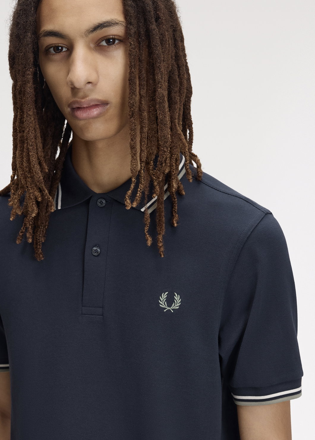Male model wearing an M3600 Twin Tipped Fred Perry Shirt in Dark Airforce / Ecru / Seagrass