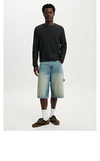 Male model wearing black long-sleeve shirt and denim shorts